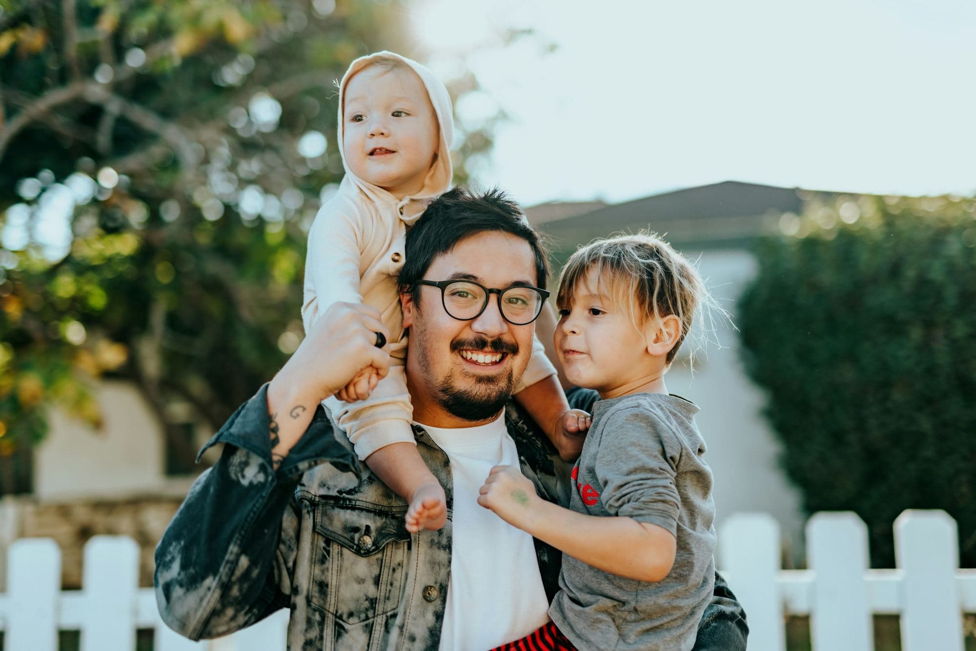 Un padre sorridente porta i suoi due figli davanti alla nuova casa