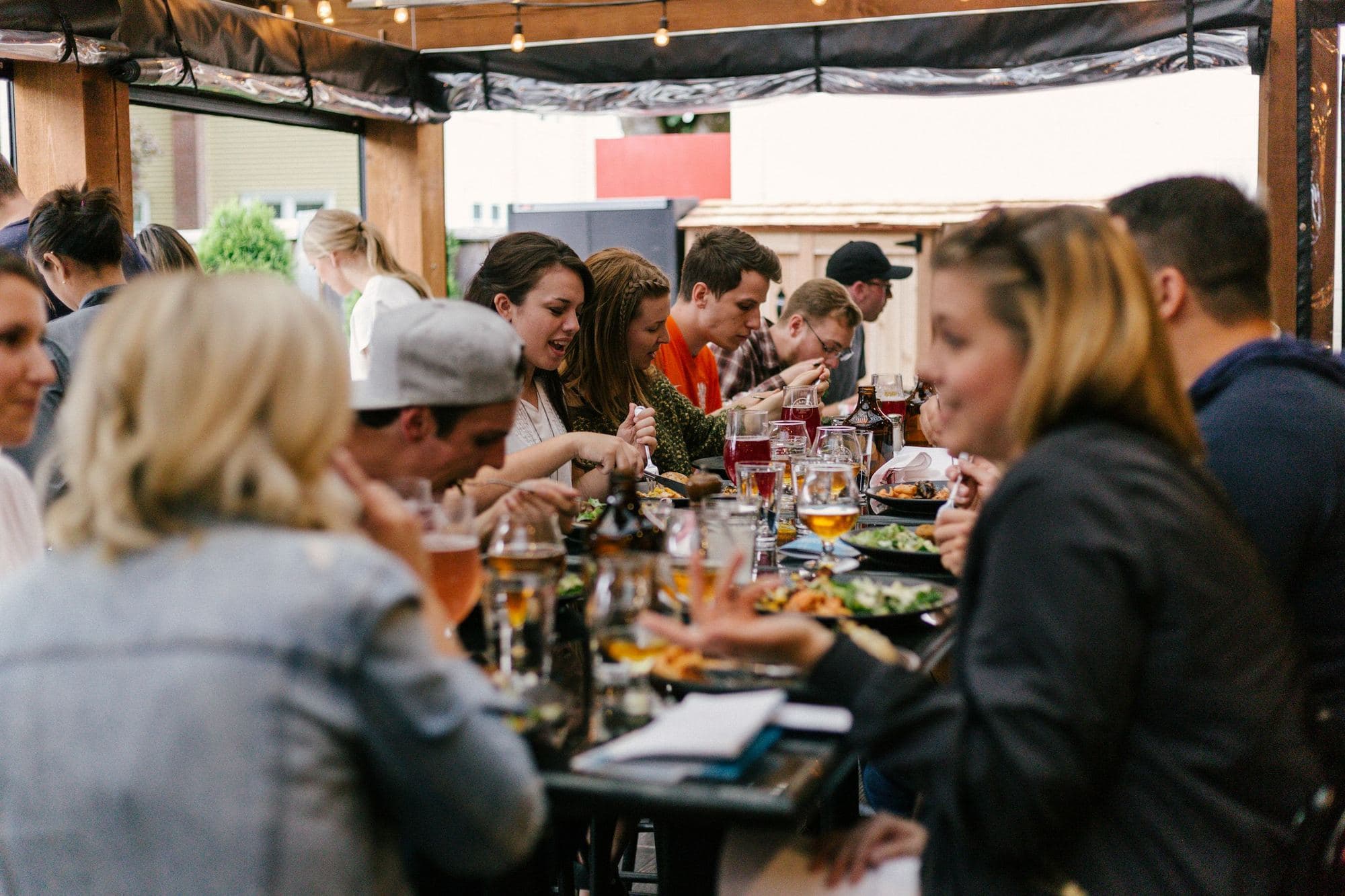 Une grande tablée d’amis de tous horizons partage un repas en terrasse